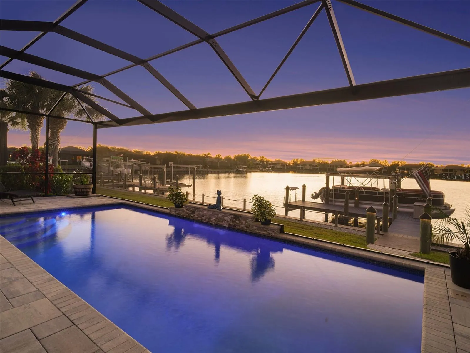 Resort style pool and spa beneath a screened enclosure, creating a private outdoor retreat with stunning evening ambiance.