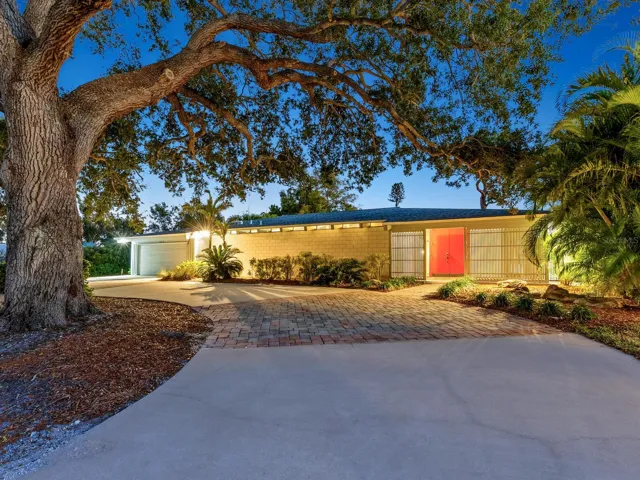 Front of home at dusk with circle driveway. Red door is entrance.