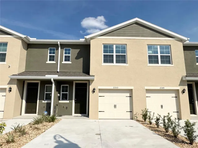 View of front of unit, long driveway, one car garage.