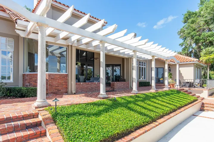 Lush landscaping and detail with an abundance of St. Louis brick and impressive pergola