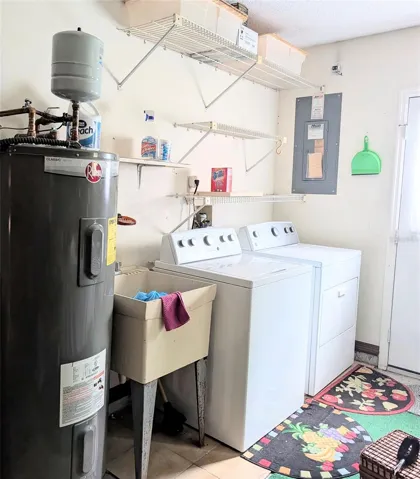 Laundry in Garage, slop sink, water heater, side door, garage door opener, and storage
