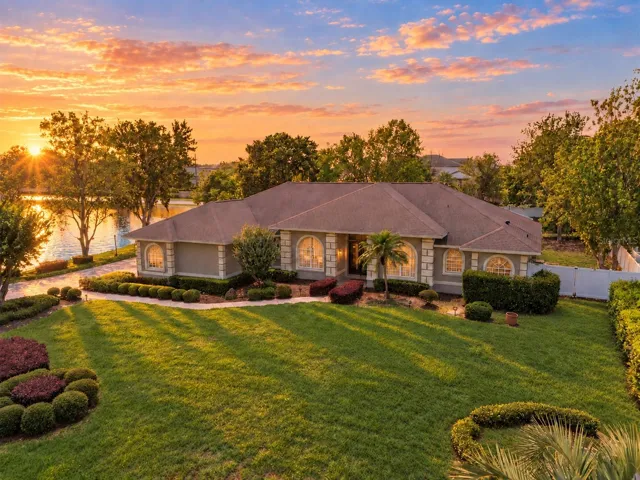 Front exterior with scenic pond views and an expansive lawn. Sunrise digitally enhanced.