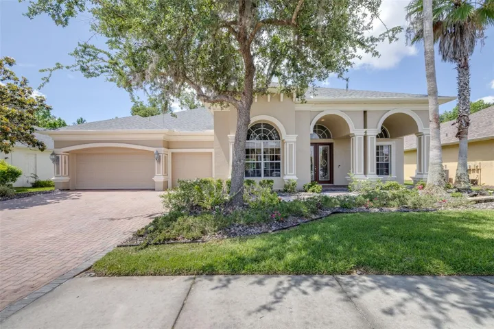 Front exterior with arched entry and mature landscaping