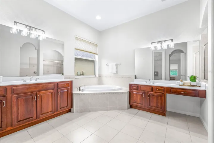 Dual vanities with jetted tub and elegant lighting throughout