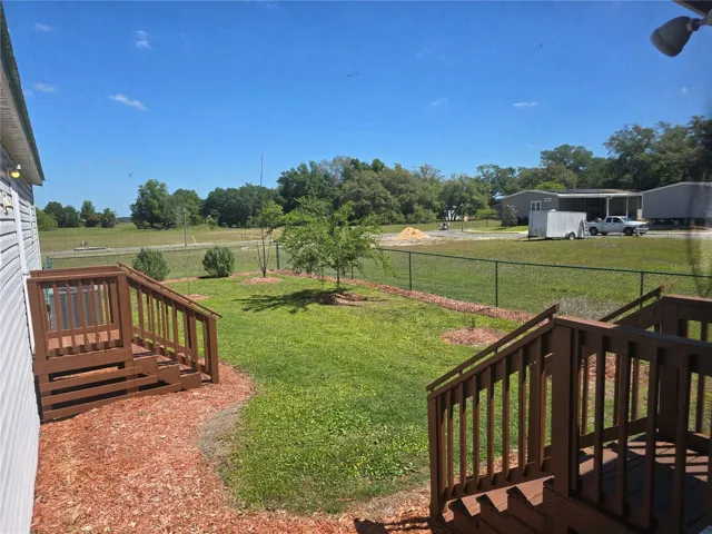 View of fenced backyard from screen enclosed patio.