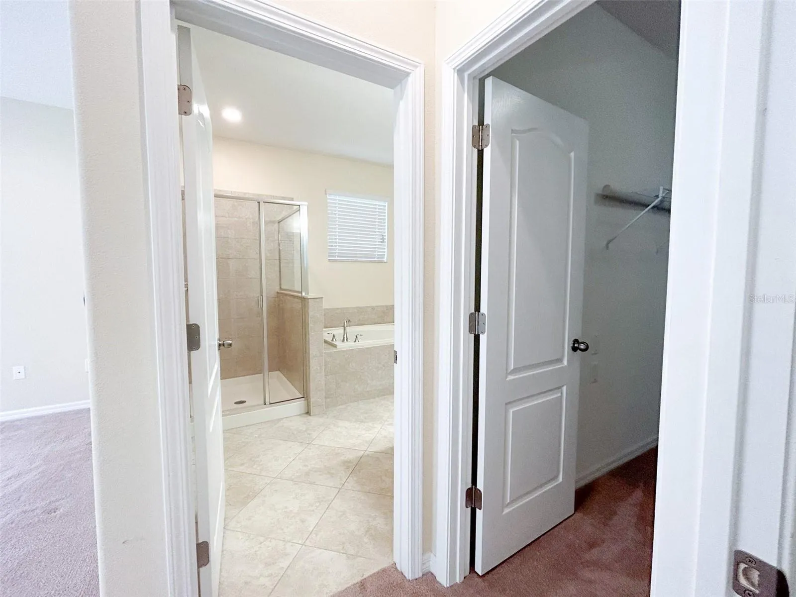 Primary bath with two separate walk-in closets with individual