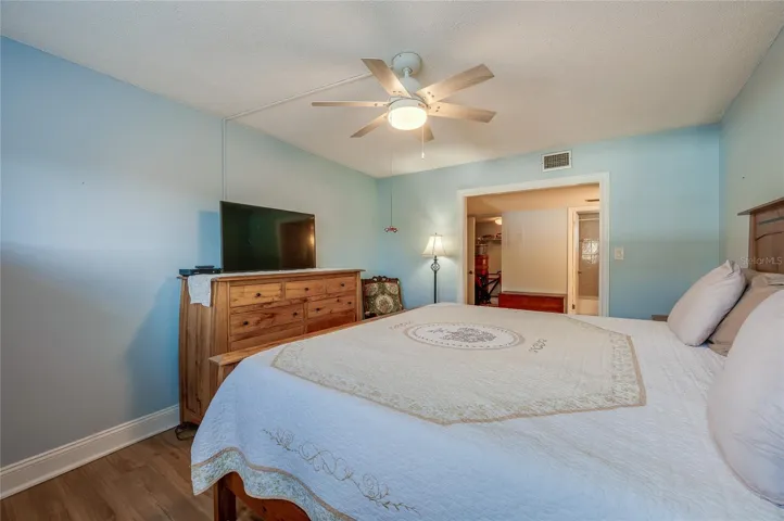 Another angle showcasing the room’s size, ceiling fan, and seamless connection to the en-suite bath and closet.