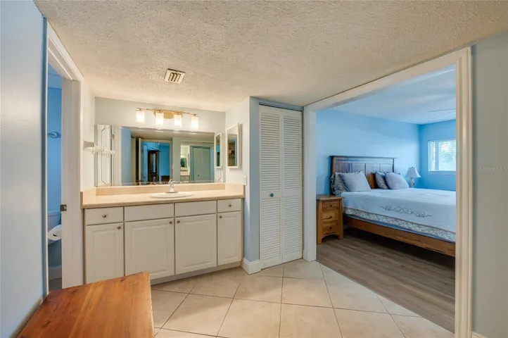 Spacious vanity area featuring an extended countertop, ample cabinetry, and a large mirror with bright overhead lighting for everyday convenience.
