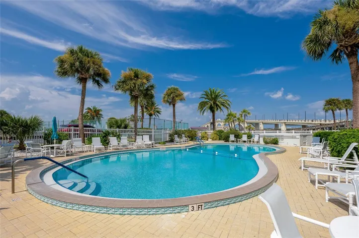 Spacious pool area with ample seating and tropical landscaping, creating a welcoming environment for residents and guests.
