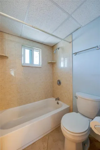 Full bathroom with a tiled tub and shower combination, complete with a window for natural light and ventilation.