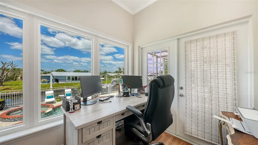 Just off the main living area, a dedicated office with French glass doors overlooks the backyard and canal