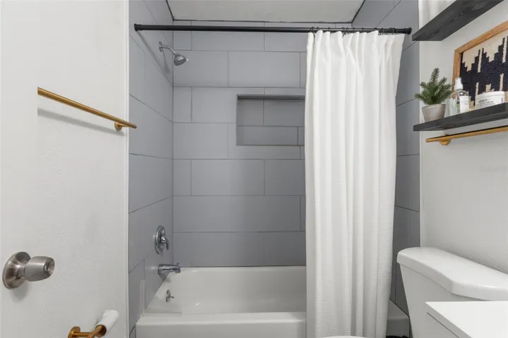 Tub/shower combination features built-in niche storage and sleek contemporary finishes.