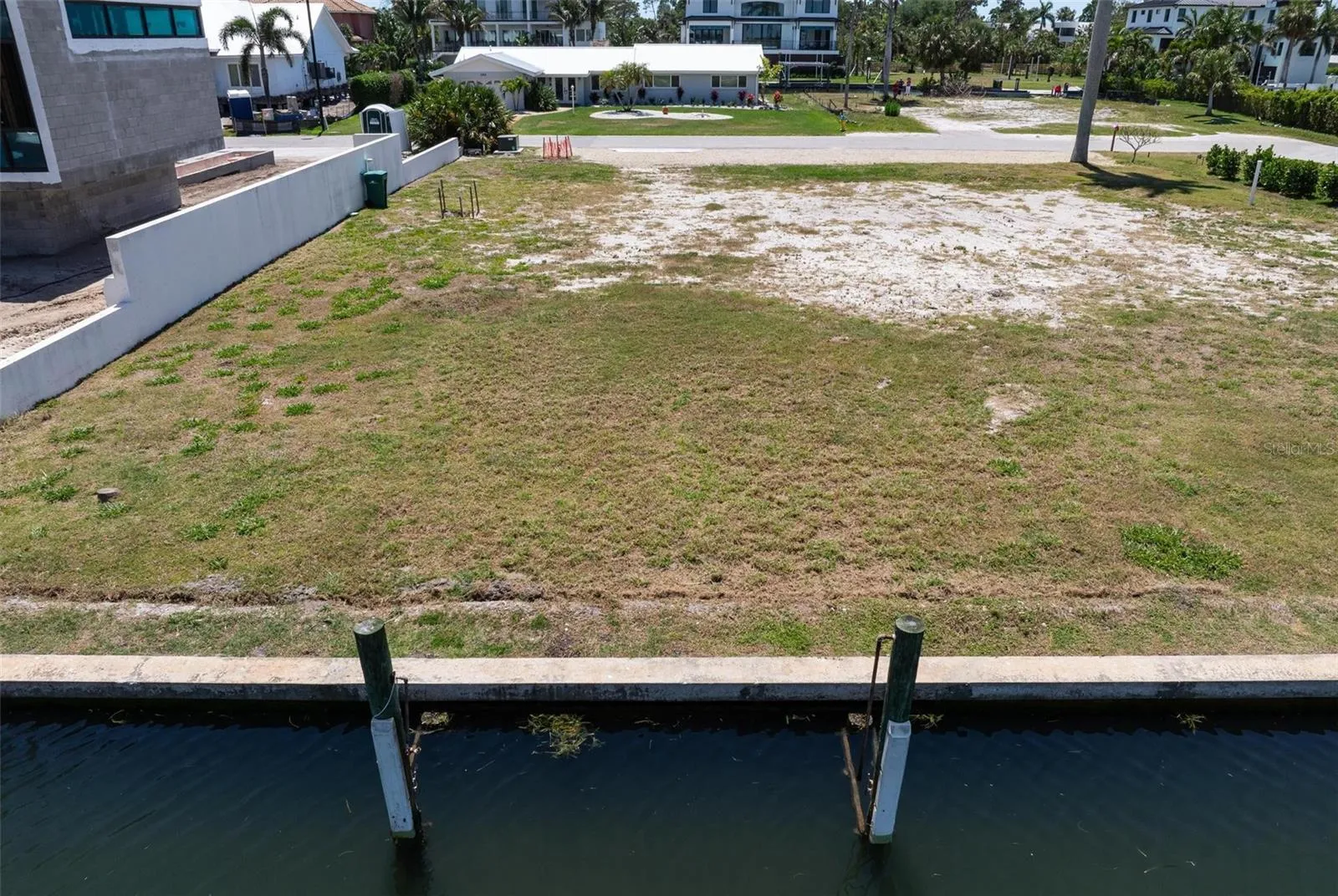 View from canal onto over quarter acre vacant lot and palm tree to right front of lot.