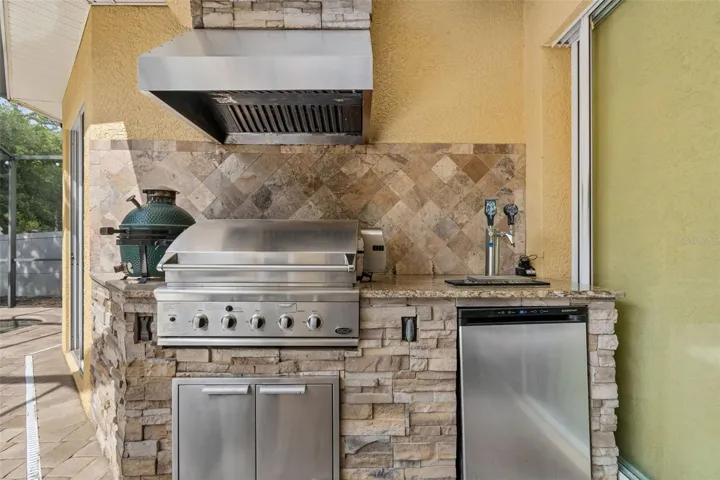 Tap, refrigerator and grill with vent hood...and surrounded by brick...very sleek!