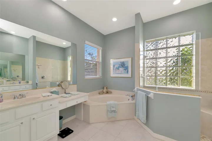 Frameless walk-in shower, twin vanities, tub & dressing table.
