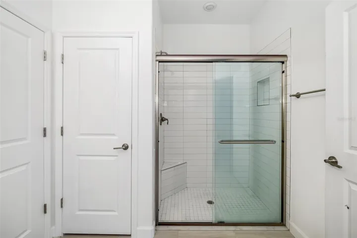 Large shower with glass enclosure and clean, modern tilework.