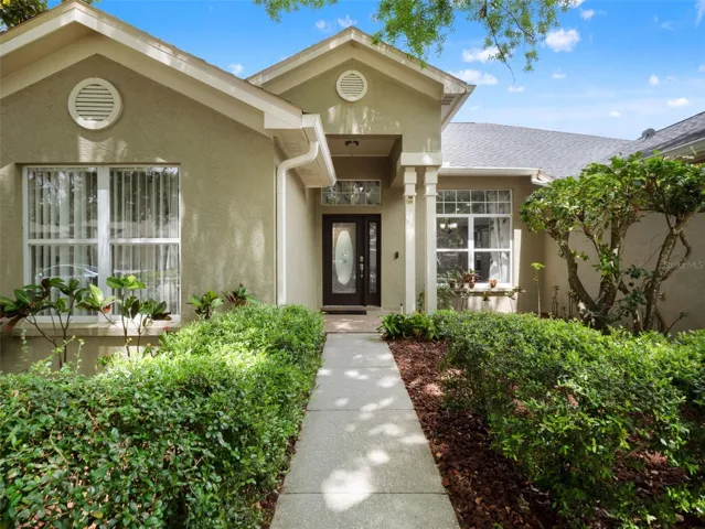 Charming curb appeal highlighted by lush greenery, established shade trees, and a manicured lawn that creates an inviting first impression.