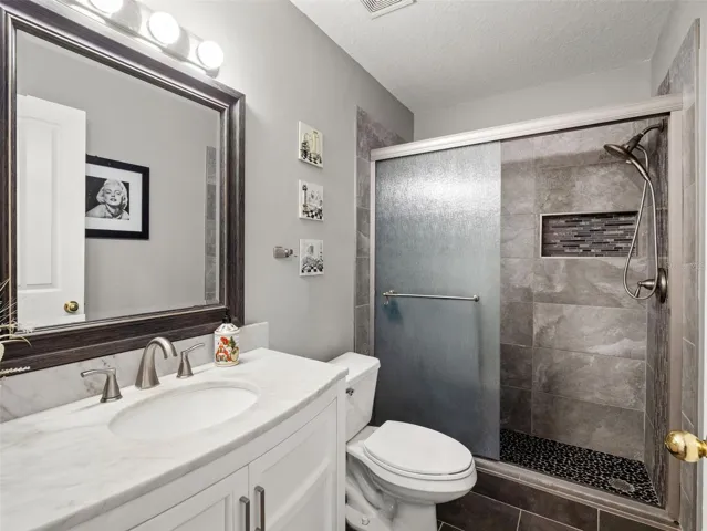 Stylishly updated bathroom with modern tile shower, glass enclosure, and sleek vanity, offering a clean and contemporary feel.