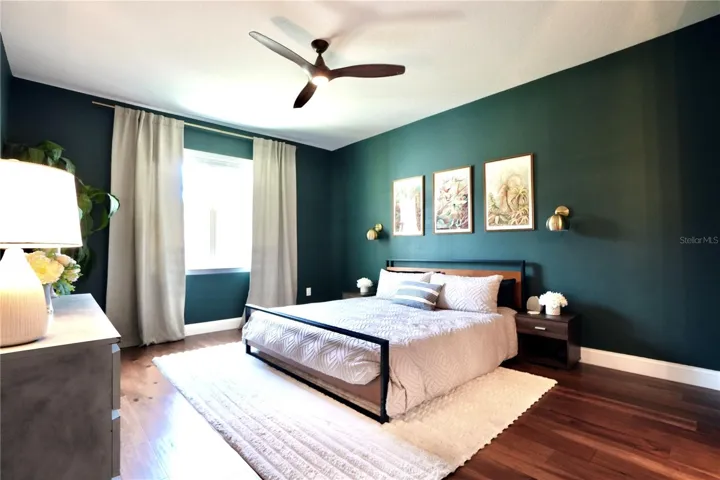Spacious primary en-suite with wood floors and ceiling fan.