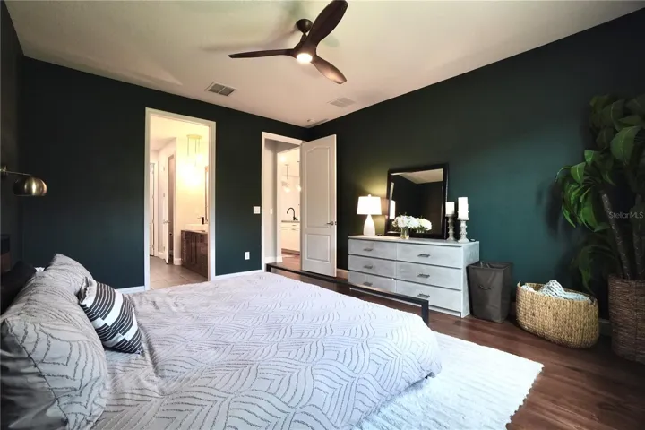 Primary bedroom with wood floors and ceiling fan.