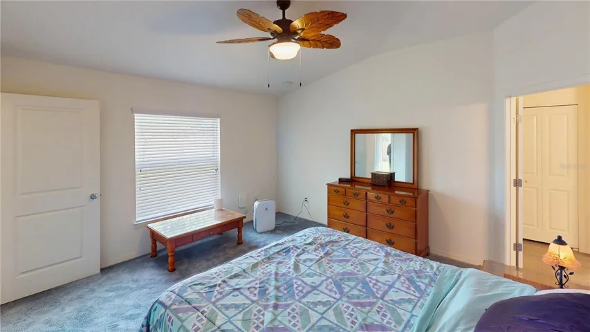 Peaceful and comfortable, the primary suite offers a relaxing retreat with a stylish leaf-blade ceiling fan and a window that brings in natural light while overlooking the private backyard.