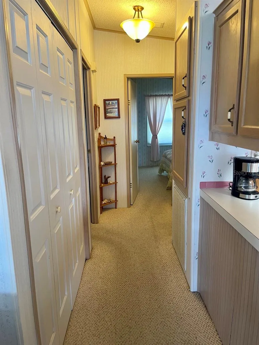 Hallway to bedrooms with indoor laundry closet