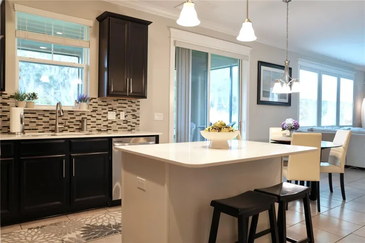 Kitchen island with breakfast bar and a window above the sink looking out to the natural beauty of the backyard.