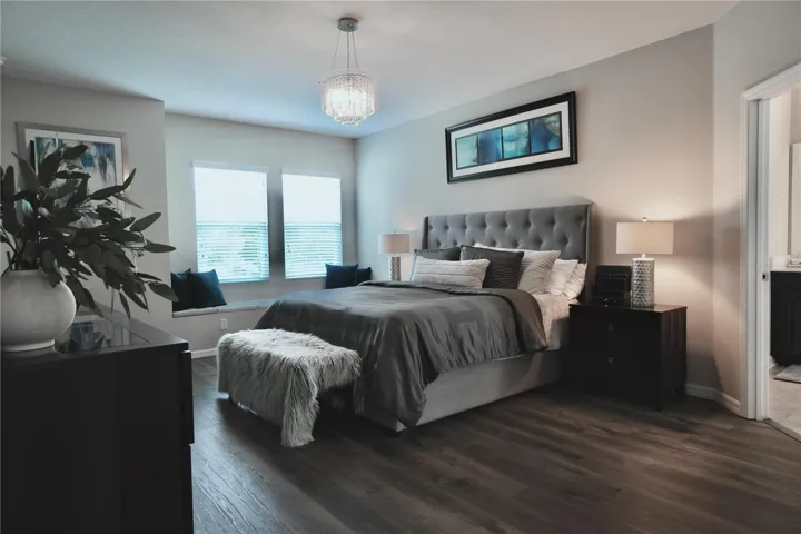 Spacious primary bedroom with a window seat and luxury vinyl plank floors.