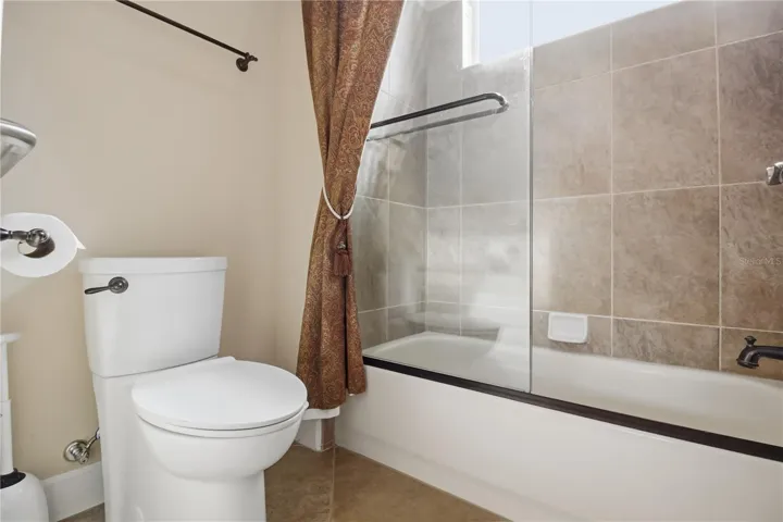 Jack and Jill bath with tub-shower combination and neutral tile finishes.
