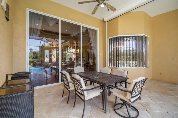 Covered lanai with outdoor dining space and peaceful views beyond the screen.