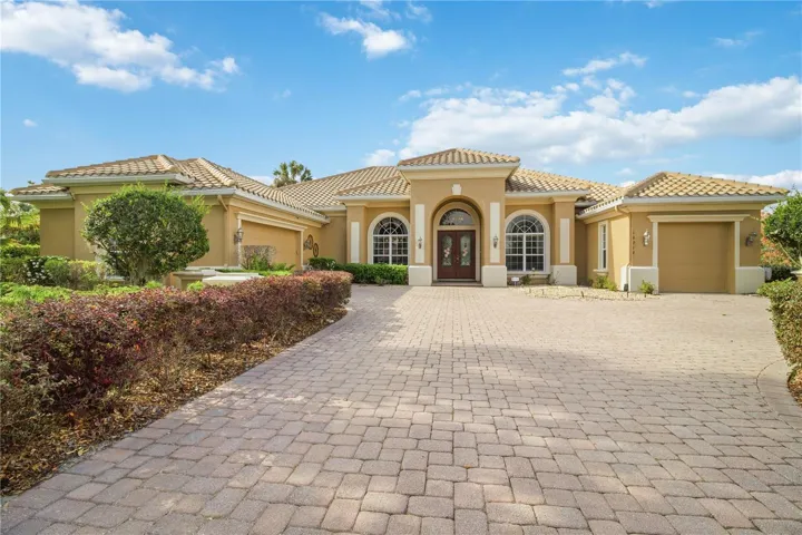 Expansive paver driveway leading to a stately arched entry.