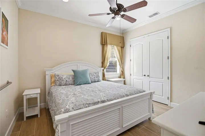 Guest bedroom with ceiling fan, natural light, and comfortable proportions.