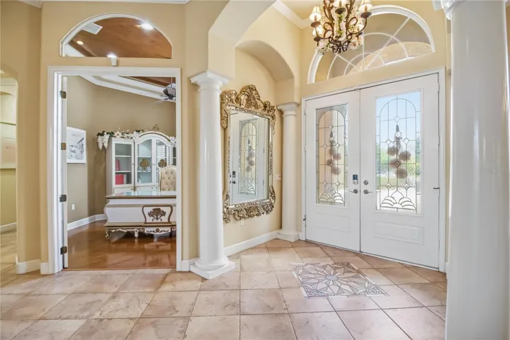 Grand foyer with soaring ceilings, columns, and elegant natural light.