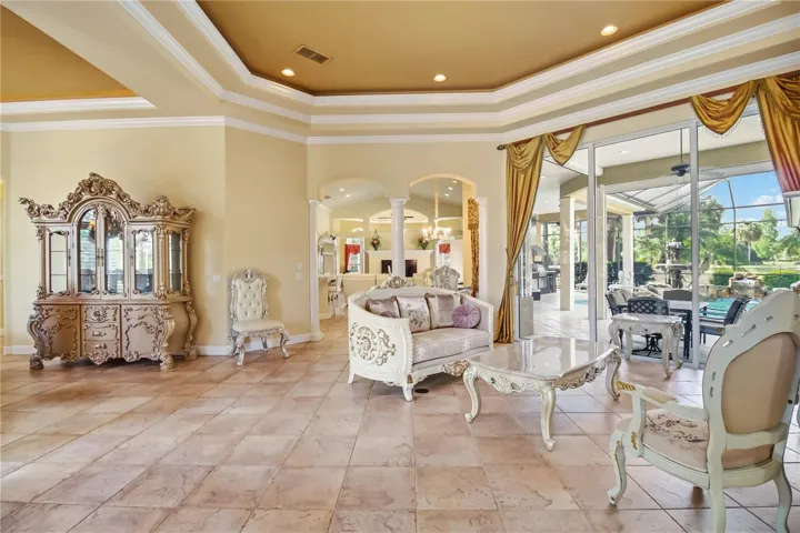 Formal living area with tray ceilings, fireplace, and views to the pool.