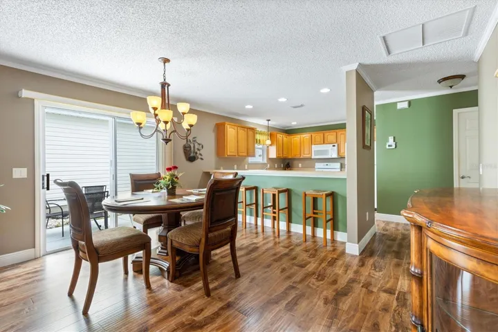 DINING ROOM LOOKING TOWARDS KITCHEN AND OUTDOOR SIDE LANAI WITH OUTDOOR SEATING AND A GRILL
