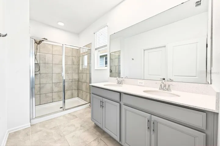 The Primary en suite bath boasts dual sinks and a step-in shower with UPGRADED SHOWERHEAD (2023).