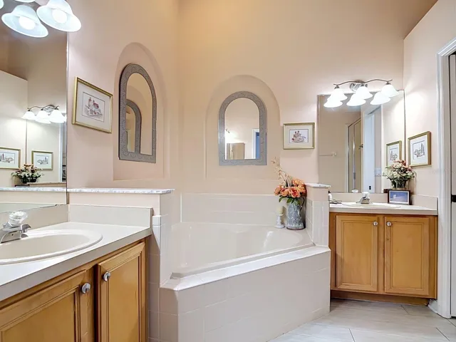 Primary ensure bathroom with dual vanities, separate shower and large tub.  High vaulted ceilings and art niches add to the spa-like vibe of the spacious private bathroom.