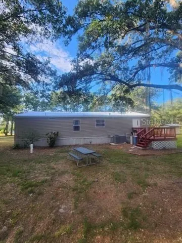 Back view of home with oak trees nestled around it.