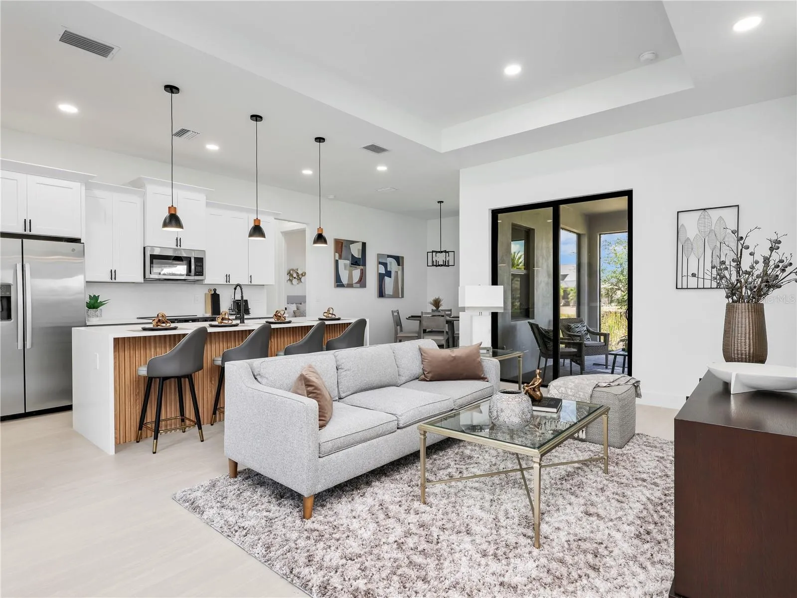 Open-concept living space featuring a kitchen island with seating, stainless steel appliances, and wood-finish flooring photos used from another listing to show what it would look like with furniture