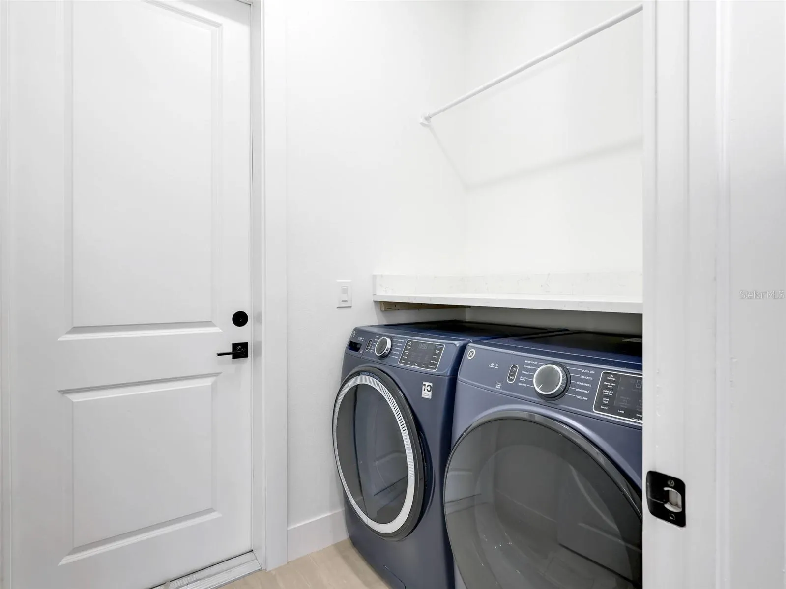 Laundry room featuring a built in shelf hanging rod and light colored flooring