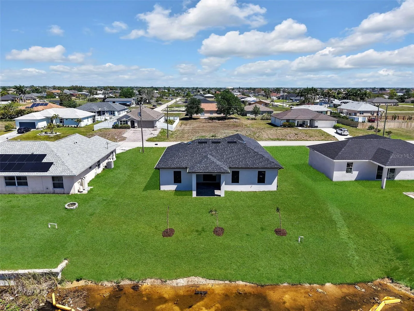 Contemporary-style home featuring a dark shingle roof and a light-colored exterior the color of the grass has been virtually enhanced