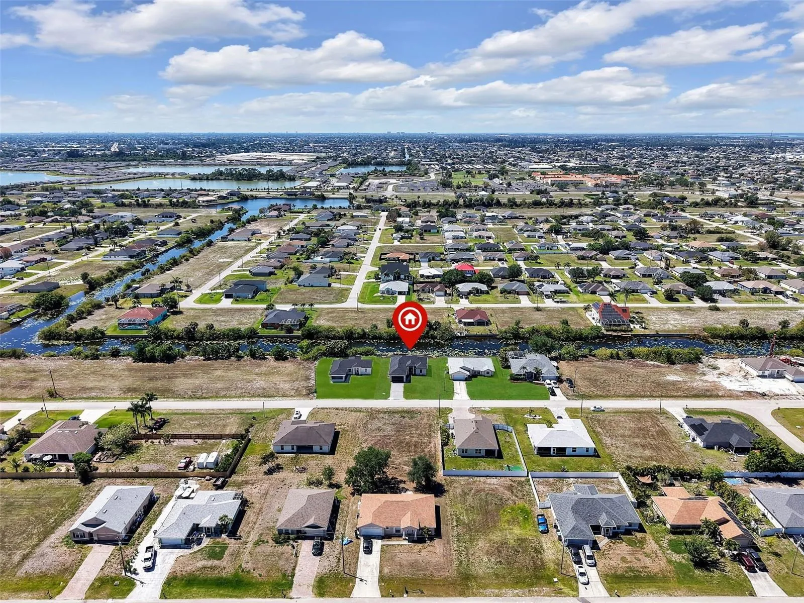 Aerial perspective showcasing a residential neighborhood with numerous single-story homes, many featuring paved driveways and green lawns the color of the grass has been virtually enhanced