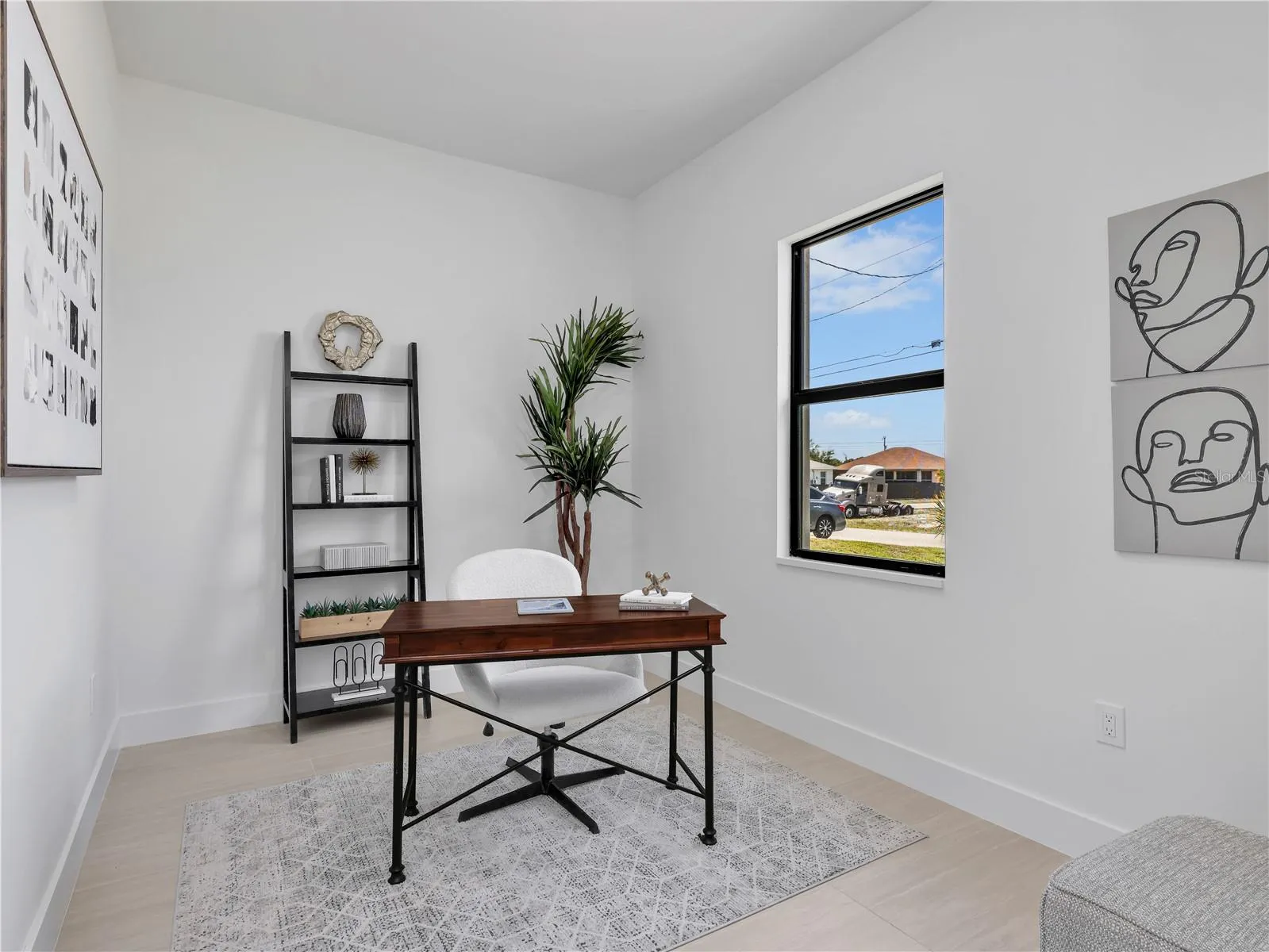 Bright room featuring a single window with black trim, light-toned flooring, and whitebaseboards photos used from another listing to show what it would look like with furniture