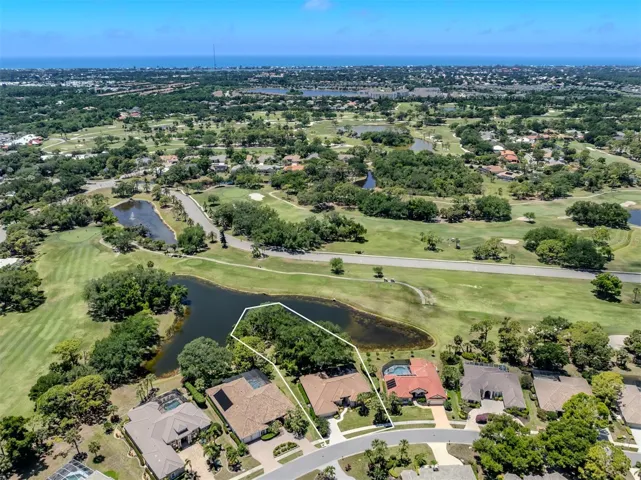 Largest lot in Calusa Lakes with wooded peninsula surrounded by golf course pond