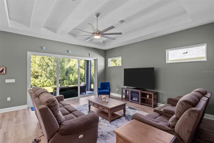 Spacious living room with high ceilings, tray detail, and decorative beam accents.