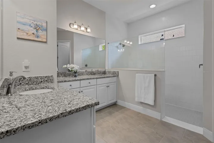 Primary bathroom with dual vanities and a large walk-in shower.