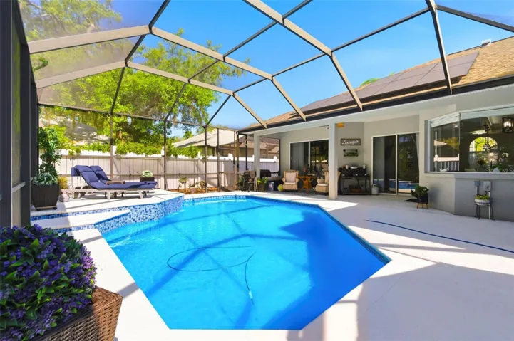 Resort-style screened-in pool area offering the perfect private outdoor retreat. Enjoy a sparkling pool surrounded by an expansive patio with ample space for lounging and entertaining. The covered lanai provides shaded seating, while sliding glass doors create seamless indoor-outdoor living. Lush landscaping and a fully fenced yard add privacy, making this space ideal for relaxing or hosting guests year-round.