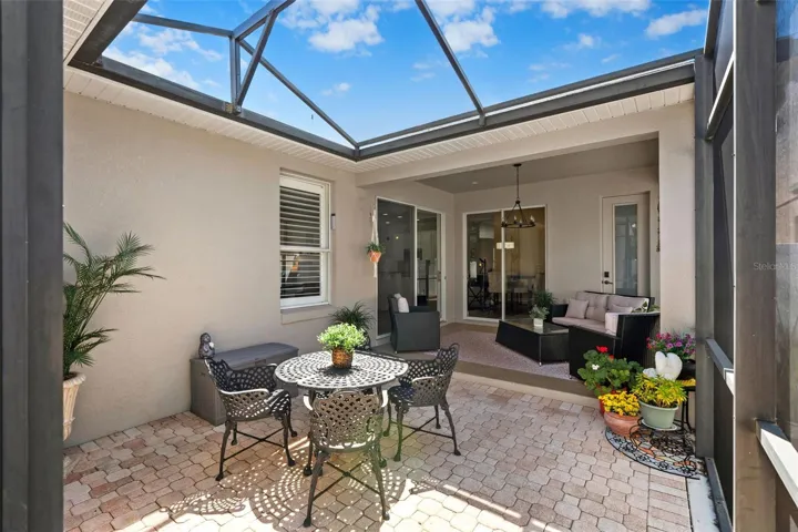 Sliding doors open to a paver patio within a PANORAMIC SCREENED ENCLOSURE, seamlessly blending indoor and outdoor living.