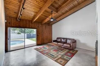 Spacious main living room featuring soaring wood-beamed ceilings and sliding doors to the pool area.