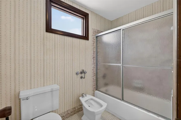 Full bath with tub and shower combination and natural light from the high window.